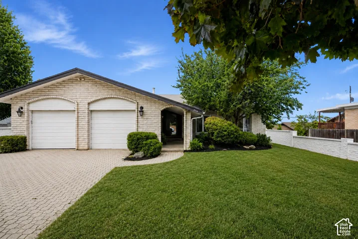 Brick exterior with a gabled roofline, dual garage bays, and a paved driveway