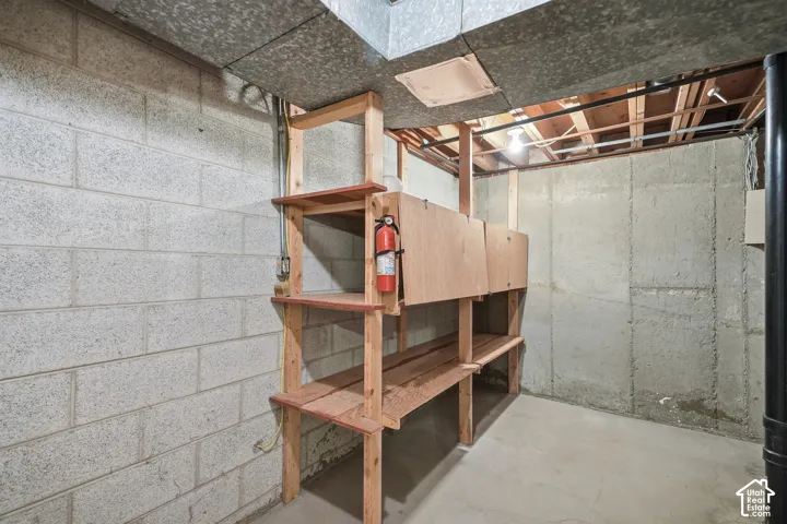 Concrete block foundation wall, built-in wooden shelving, and concrete floor