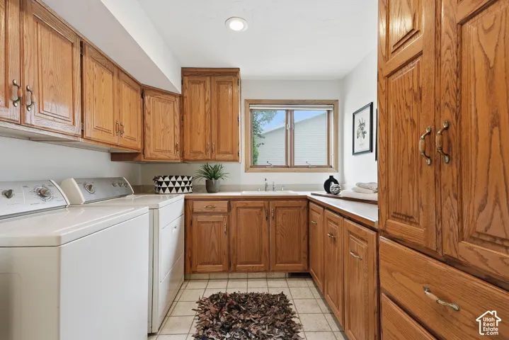 Extensive wood cabinetry, sink basin, white tile flooring, and overhead lighting