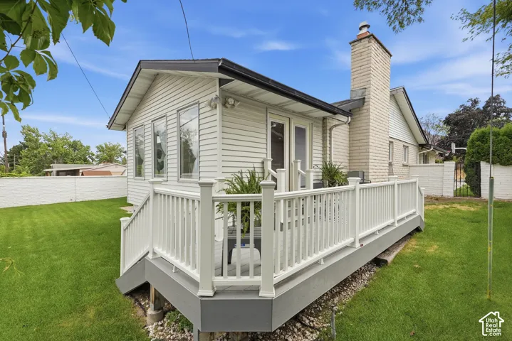 Elevated deck with white balusters, leading to an exterior extension with three vertical windows