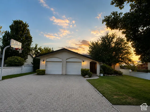 White brick exterior with a two-car garage, extensive paver driveway, and established landscaping