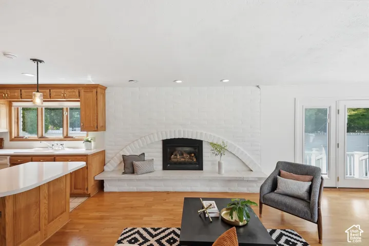 White-painted brick fireplace with an arched hearth, wood-finish flooring, wood cabinetry, built-in kitchen island with white countertop, and glass-paned doors