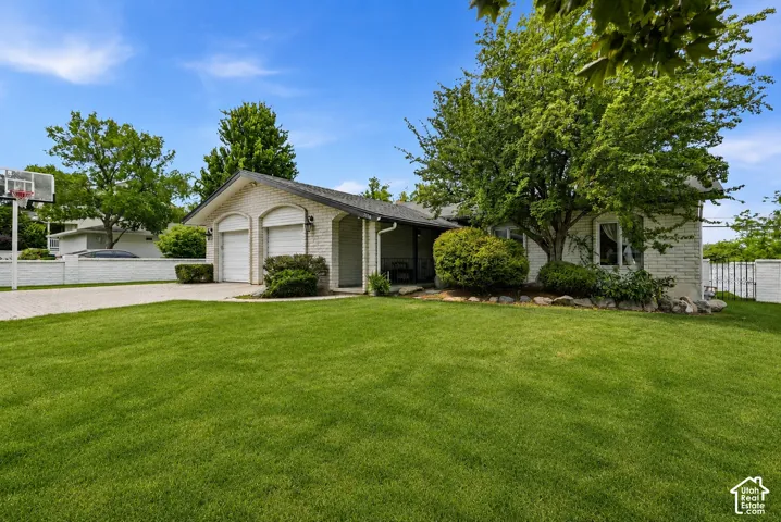 White brick exterior with a two-car garage, established landscaping, and a paved driveway