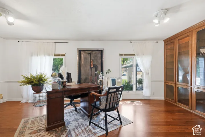 Wood-finish flooring, white walls with wainscoting, and a built-in wooden cabinet with glass doors