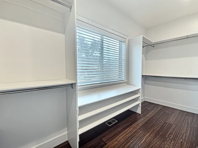 Primary Bedroom with a built-in closet system featuring multiple shelves, hanging rods, and a window with blinds