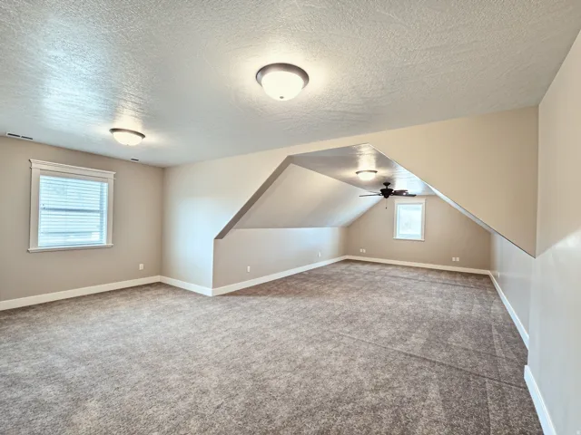 Expansive room featuring textured carpeting, multiple windows, and recessed lighting