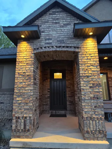 Brick exterior with an arched entryway and grand entry dark-paneled door