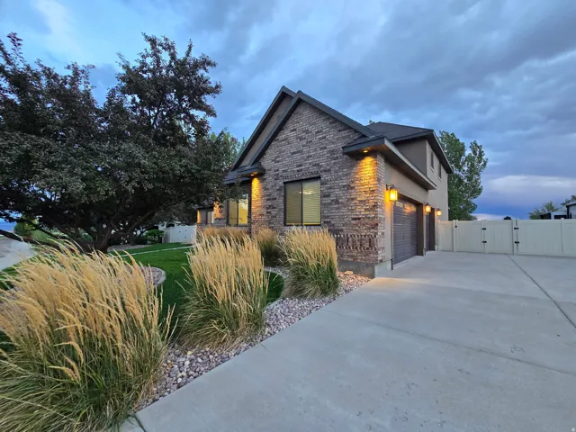 Brick and stucco exterior with integrated garage, large driveway, and a gated side yard