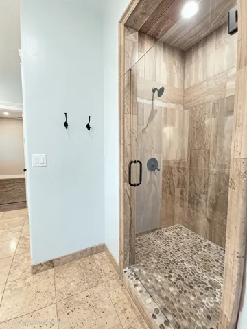 Frameless glass shower enclosure featuring natural stone tile surround, double shower heads and a river rock shower floor