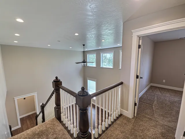 A beautiful view from the top of the landing featuring large picture windows allowing ample natural light, an expansive and picturesque grand stair case a beautifully carved newel post.