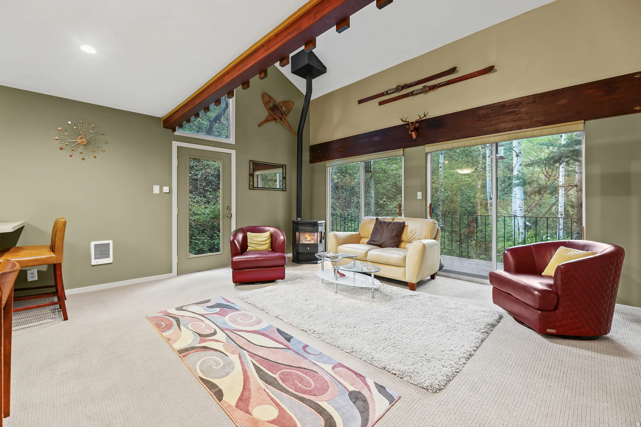 Living room with open vaulted ceiling with multiple glass doors offering exterior access