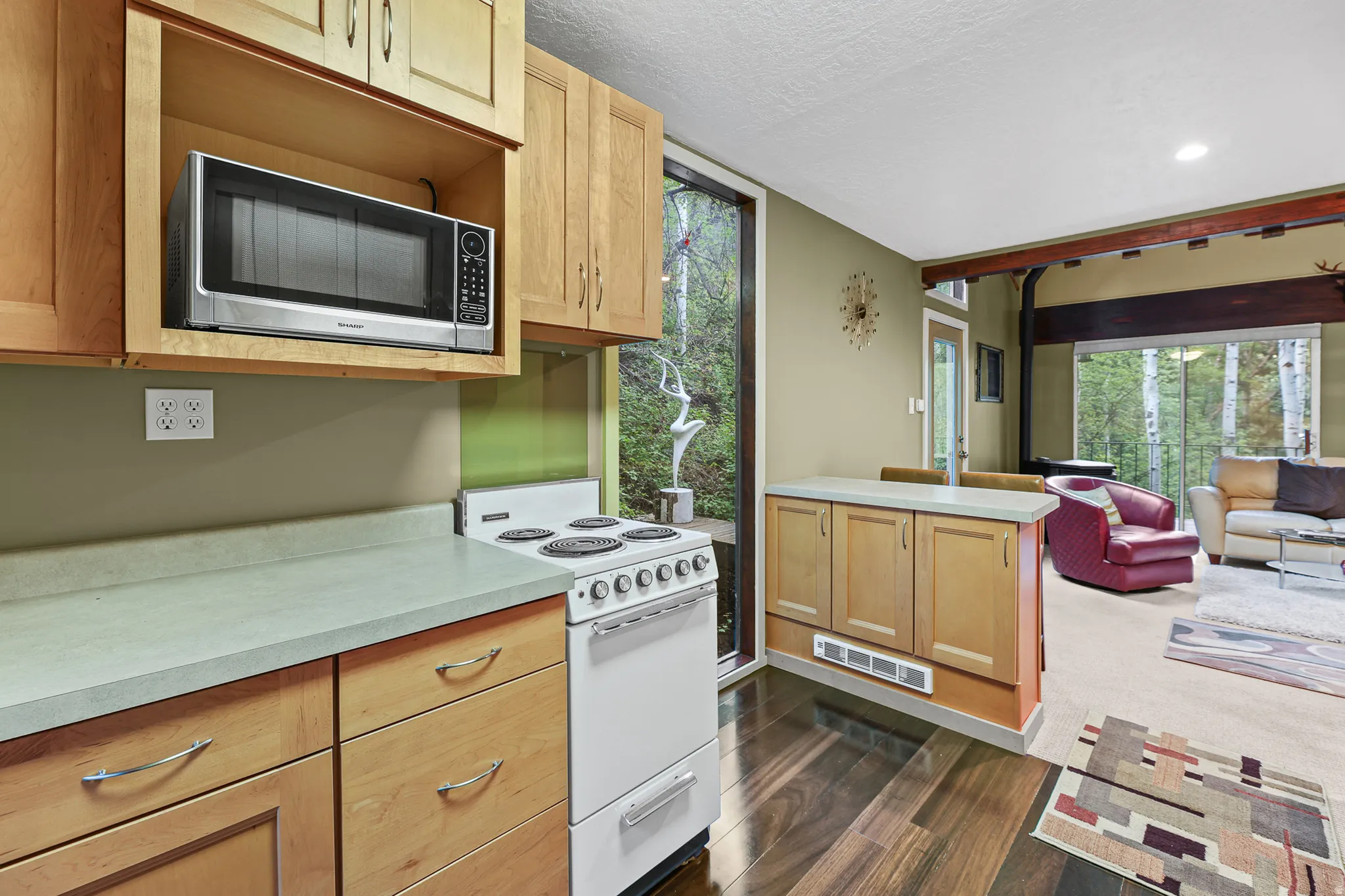 Kitchen featuring wood-finish flooring, light wood cabinetry, light-toned countertops, and bar for eating space.