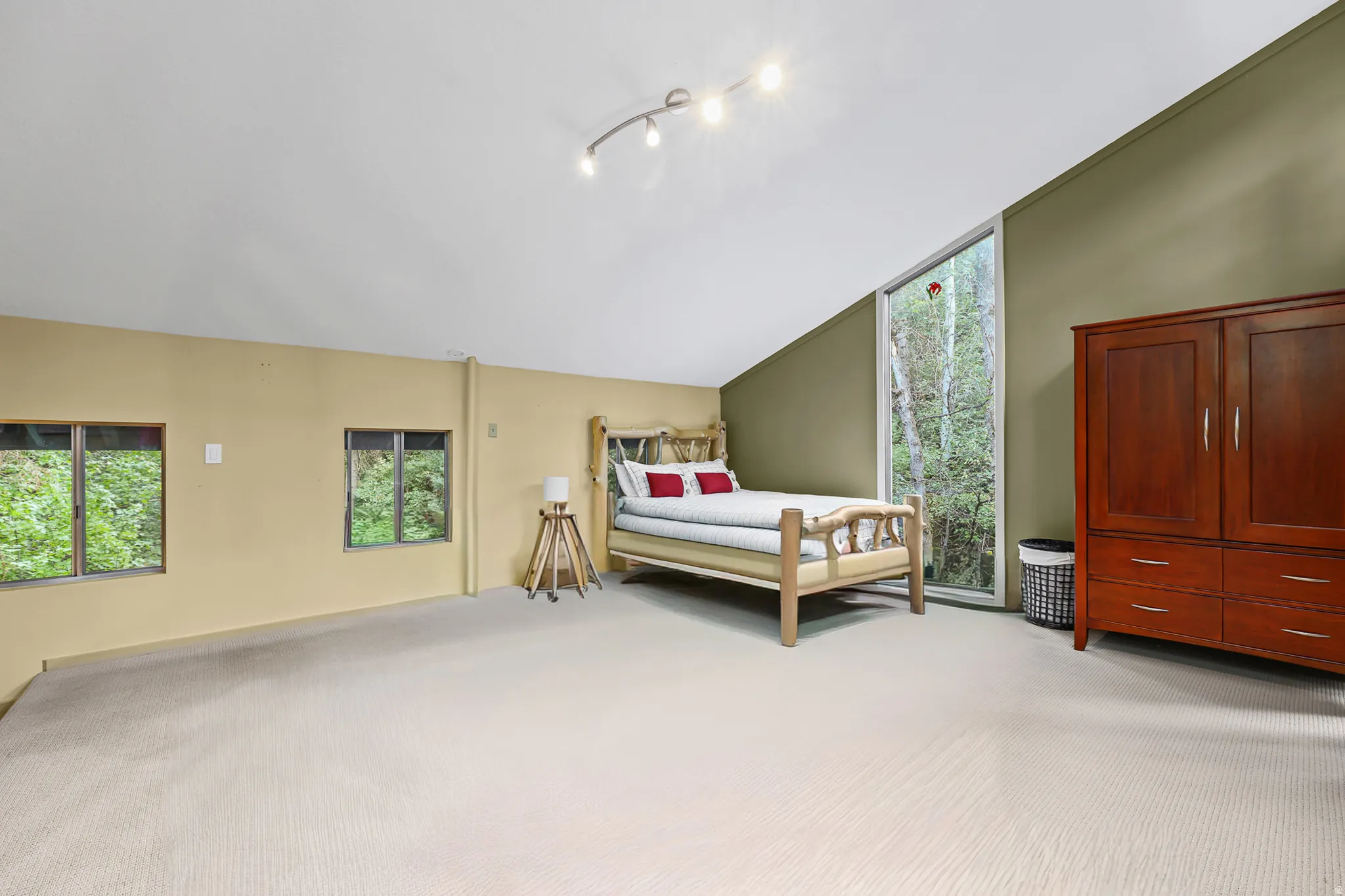 Sloped ceilings with track lighting, multiple windows, and light-colored carpeting*Photo has been edited to take out pool table*