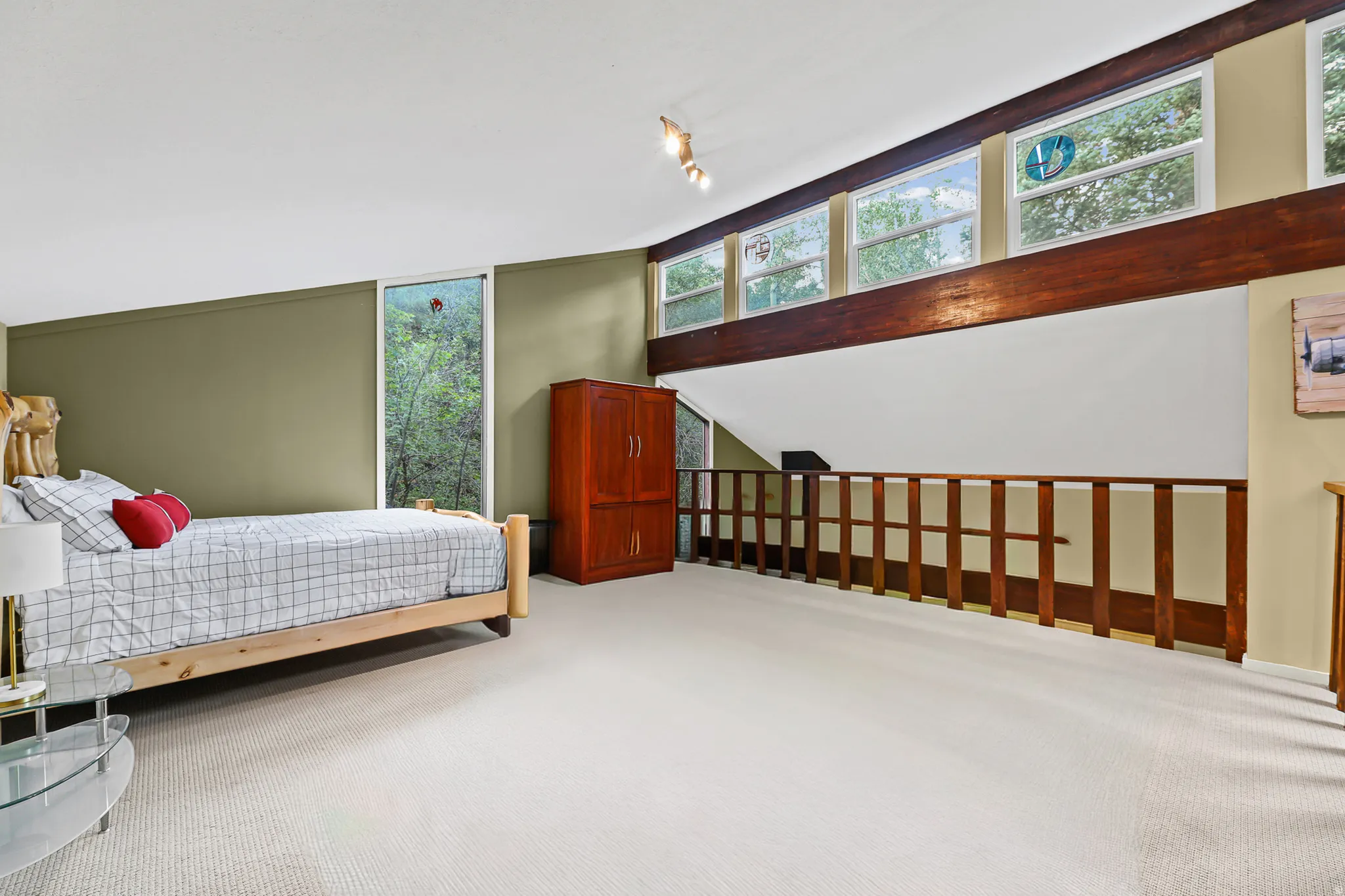 Loft space with carpeting, wood-finish railing, an exposed wood beam, a full-height window, and transom windows*Photo has been edited to take out pool table*