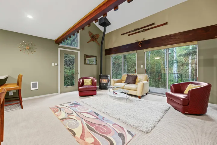 Living room with open vaulted ceiling with multiple glass doors offering exterior access