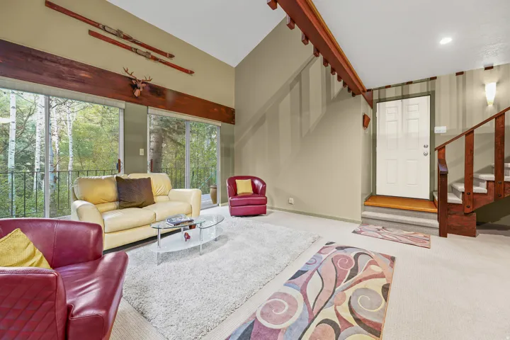 Vaulted ceiling living area featuring multiple glass sliding doors