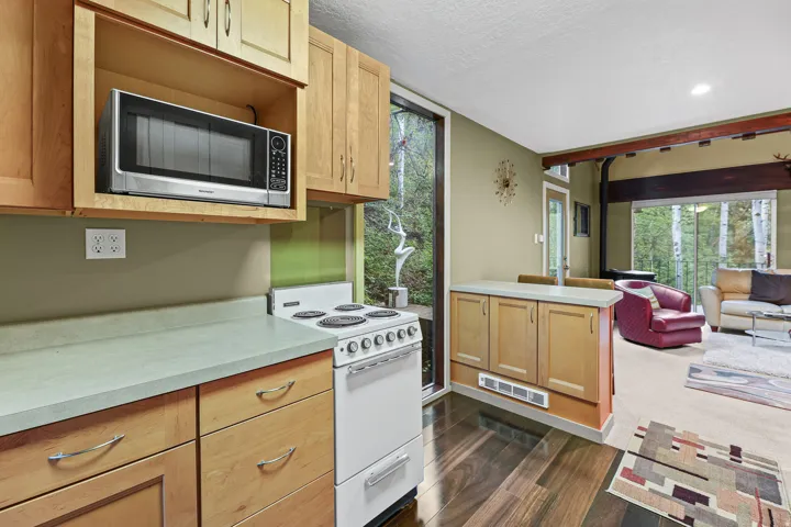 Kitchen featuring wood-finish flooring, light wood cabinetry, light-toned countertops, and bar for eating space.