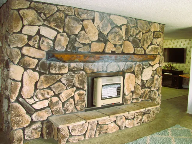 Stone-clad fireplace with a natural wood mantel and stone hearth