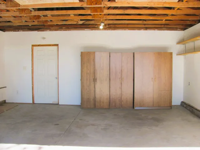 Concrete flooring with built-in wood-finish cabinetry and exposed wood ceiling joists
