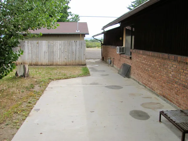 Concrete pathway with a brick exterior wall and a wood-sided outbuilding