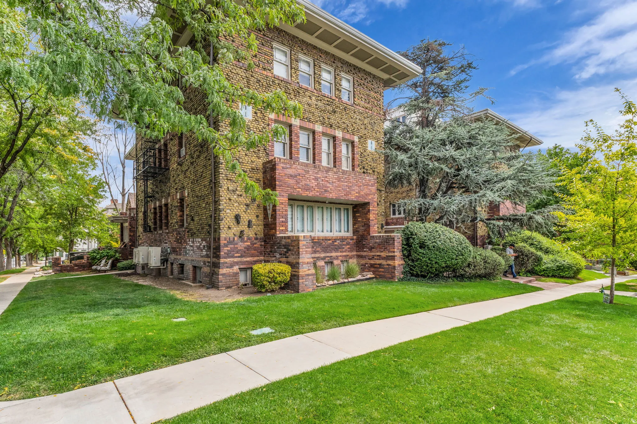 Brick and stone exterior with multiple windows, featuring a sidewalk and green lawn
