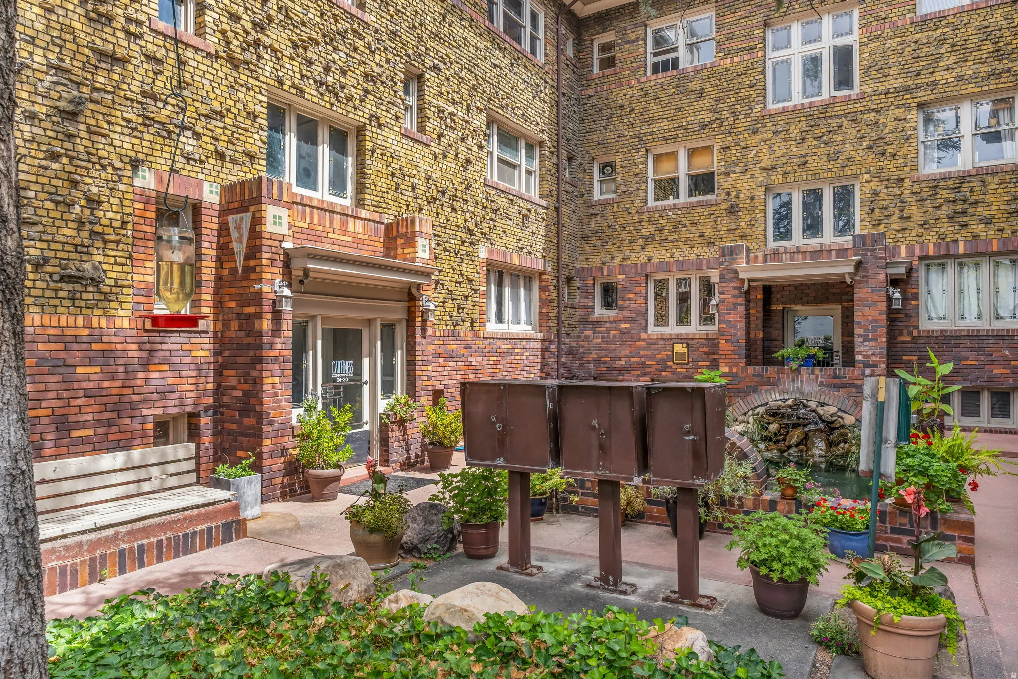 Brick exterior with contrasting brickwork accents, multiple windows, built-in wooden bench, and a stone water feature