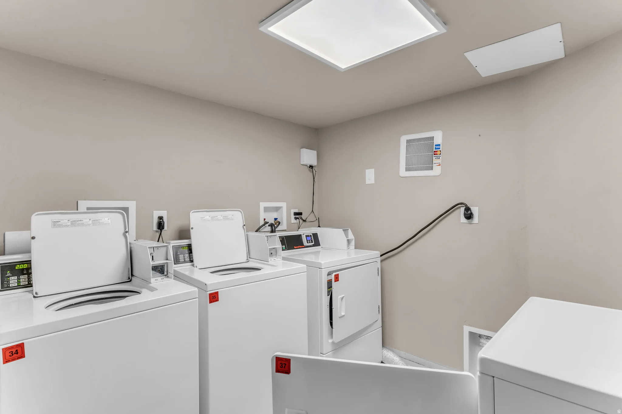 Laundry area with multiple top-load washing machines and front-load dryers