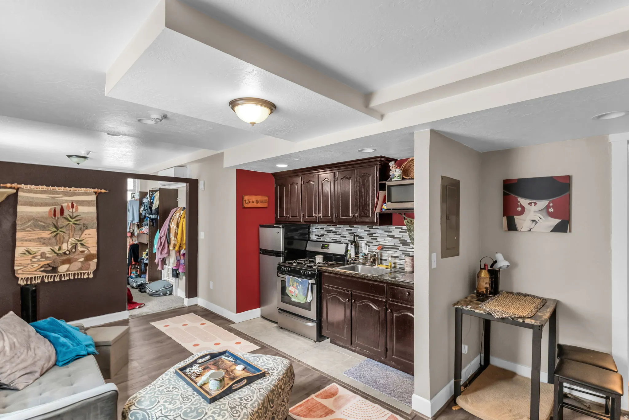Compact kitchen featuring wood-finish cabinetry, stainless steel appliances, and a tiled backsplash
