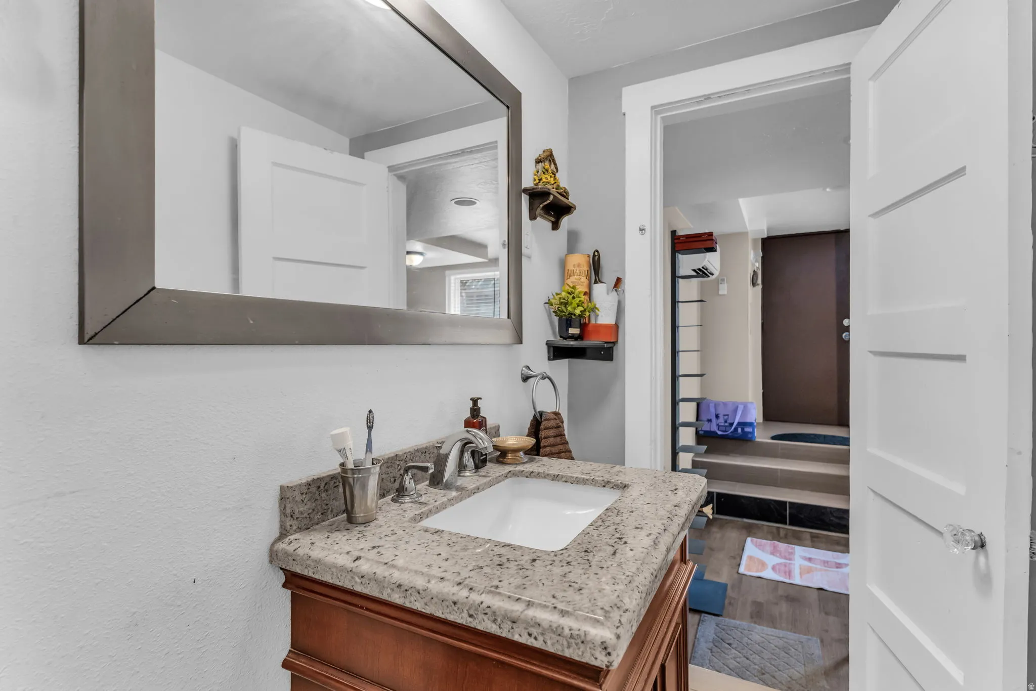 Vanity with a granite countertop and an integrated sink, framed mirror, and wood-finish cabinetry