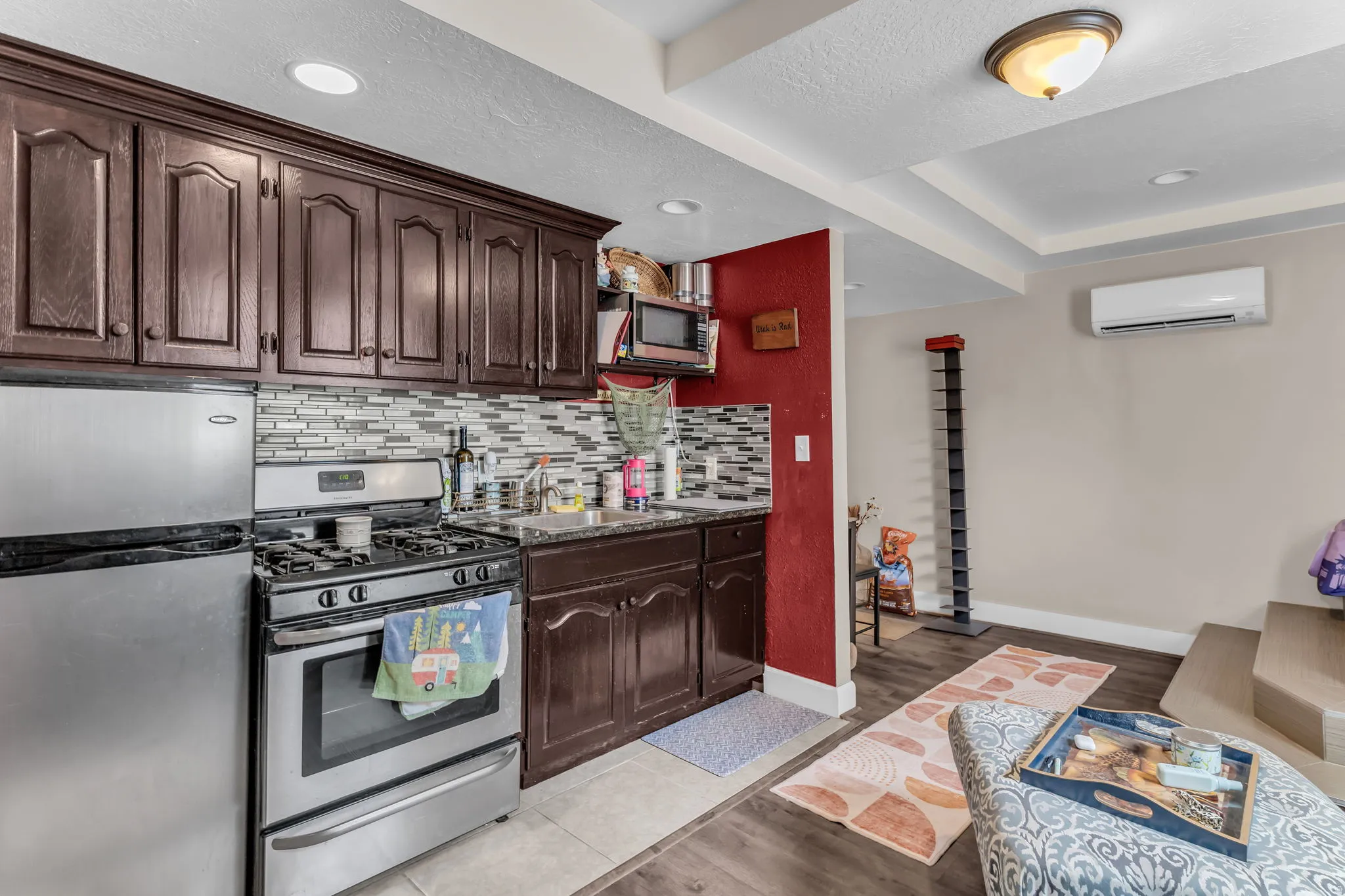 Kitchenette featuring dark wood cabinetry, stainless steel appliances, and a tiled backsplash