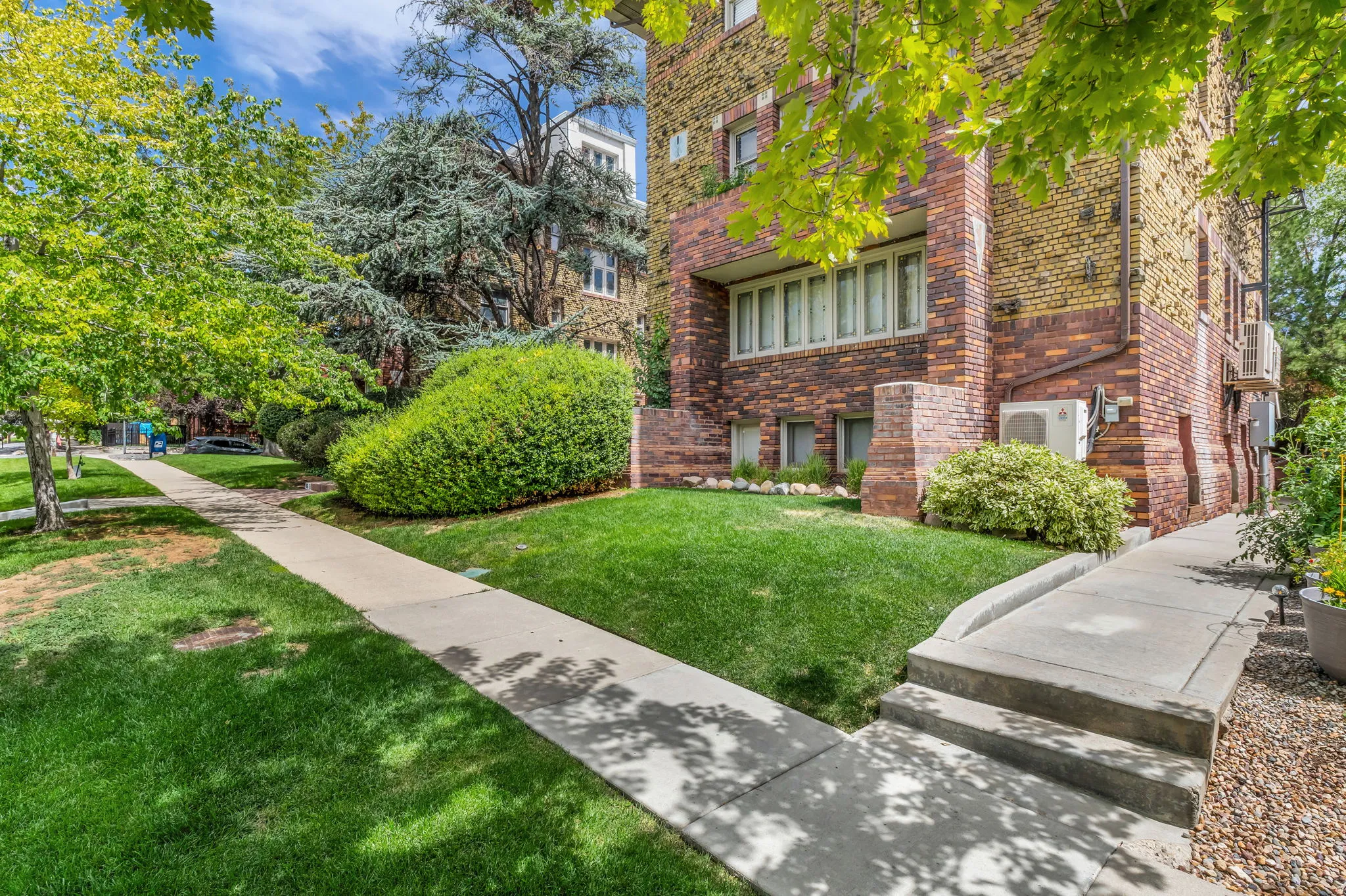 Brick exterior with varied brickwork, mature landscaping, concrete walkways, and a ramp entrance