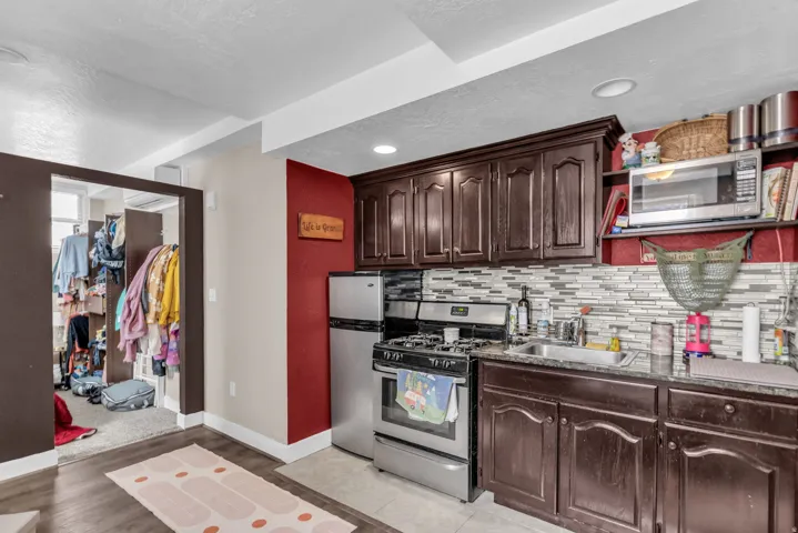 Kitchenette featuring dark wood cabinetry, stainless steel appliances, a mosaic tile backsplash, and recessed lighting