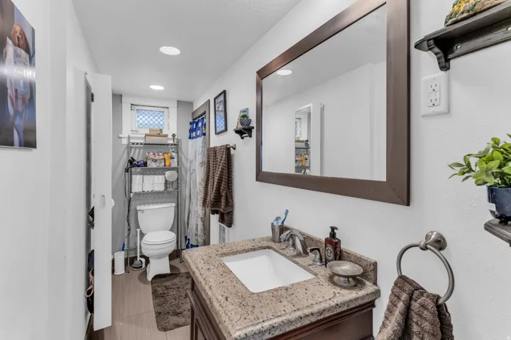 Bathroom featuring a vanity with an integrated sink, a rectangular framed mirror, recessed lighting, and wood-finish flooring