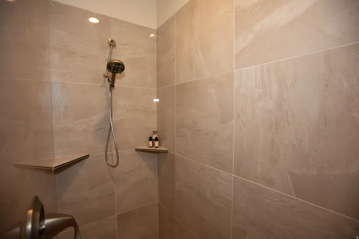 Tiled shower featuring a handheld showerhead, recessed lighting, and integrated corner shelving