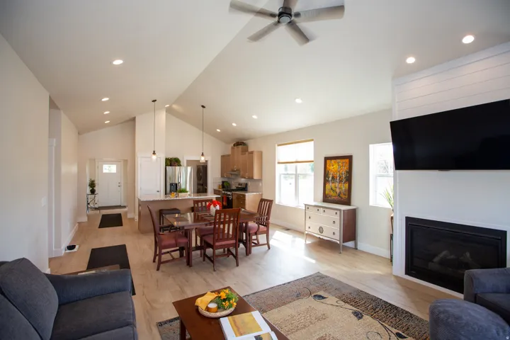 Vaulted ceilings with recessed lighting, wood-finish flooring, built-in fireplace, kitchen island with seating, and wood cabinetry
