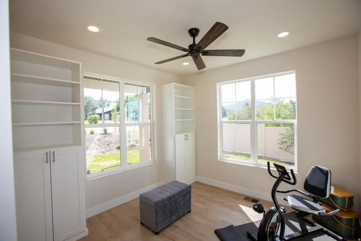 Flex Room with recessed lighting, wood-finish flooring, two built-in storage units, and a ceiling fan with dark wood-finish blades