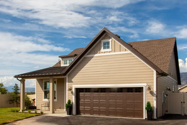 Two-story property with horizontal siding, an attached two-car garage, a covered entry, and a dormer window