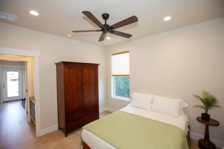 Recessed lighting, ceiling fan, window with roller shade, and wood-finish flooring