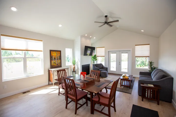 Vaulted ceiling with a ceiling fan, recessed lighting, wood-finish flooring, white shiplap fireplace, and double French doors