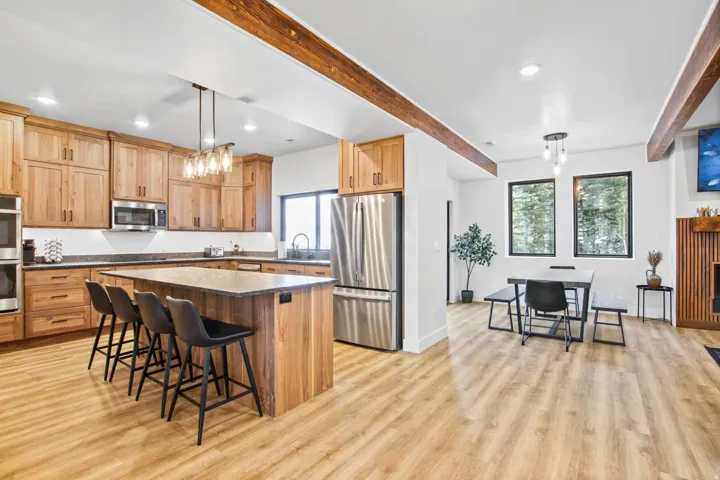 Open-concept living space with wood-finish flooring, exposed ceiling beams, and recessed lighting