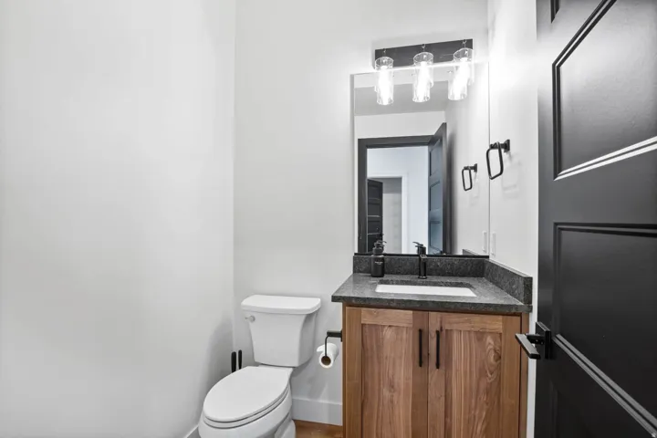 Wood-finish vanity with dark countertop, undermount sink, and matte black faucet