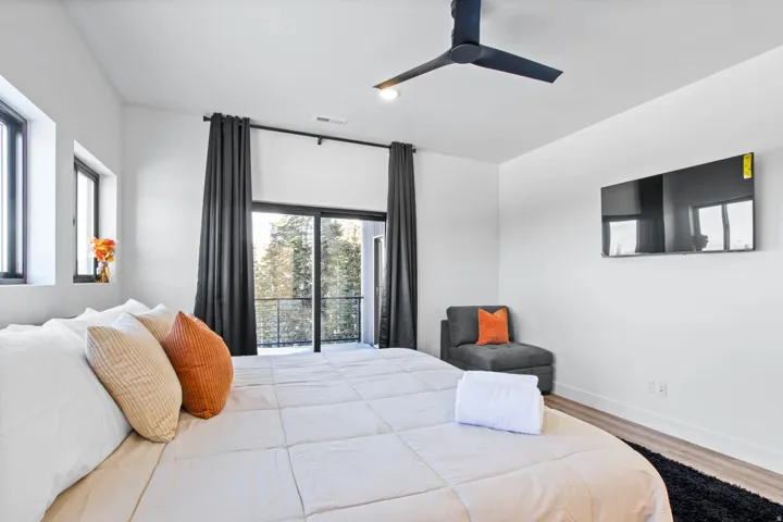 Spacious room featuring multiple windows, a ceiling fan, and a wall-mounted display