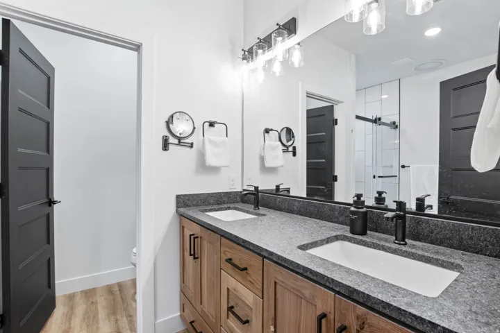Dual vanity bathroom featuring wood-finish cabinetry, quartz countertops, and undermount sinks
