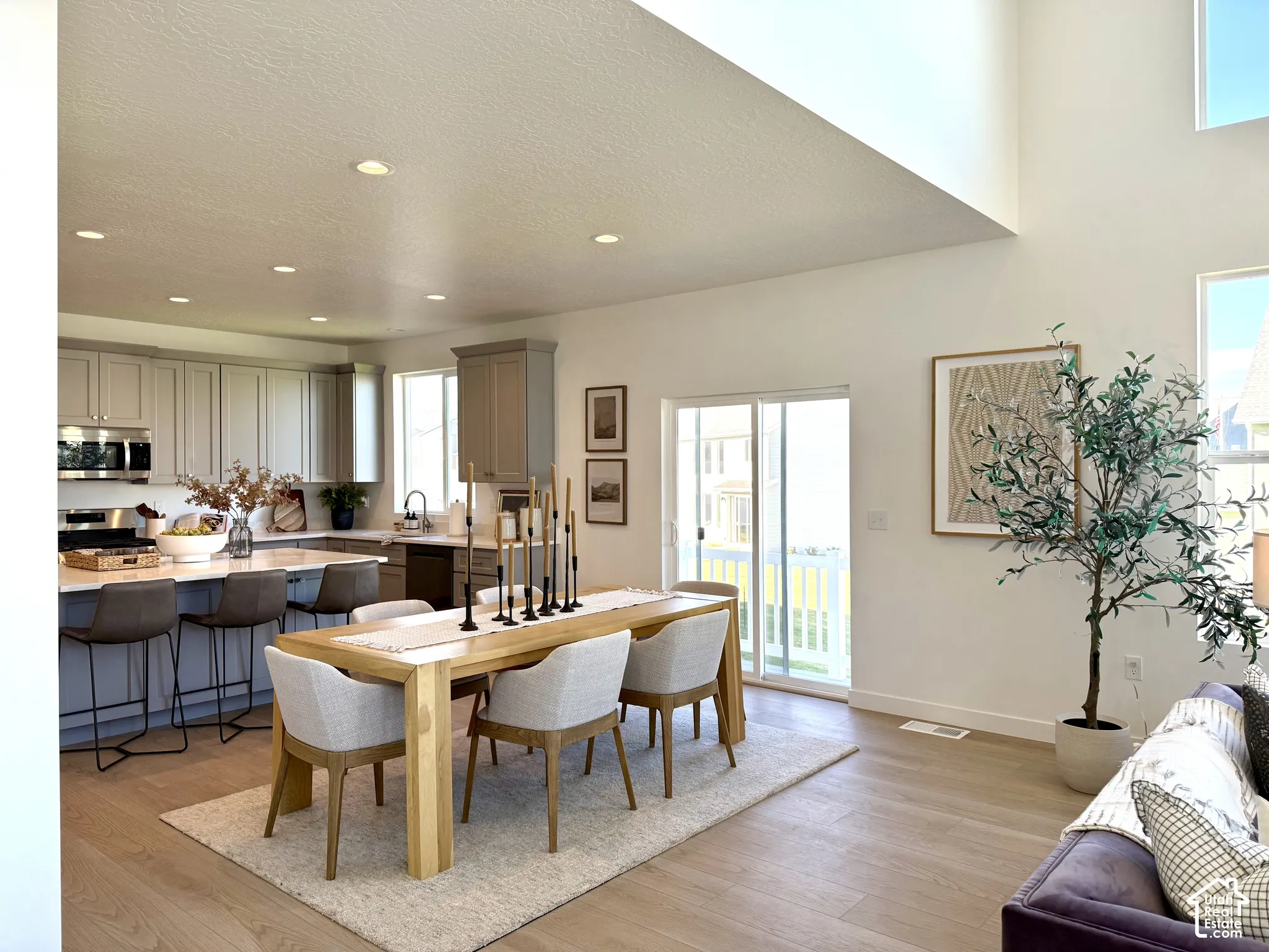 Open-concept living area featuring wood-finish flooring, a kitchen island with seating, stainless steel appliances, and a sliding glass door