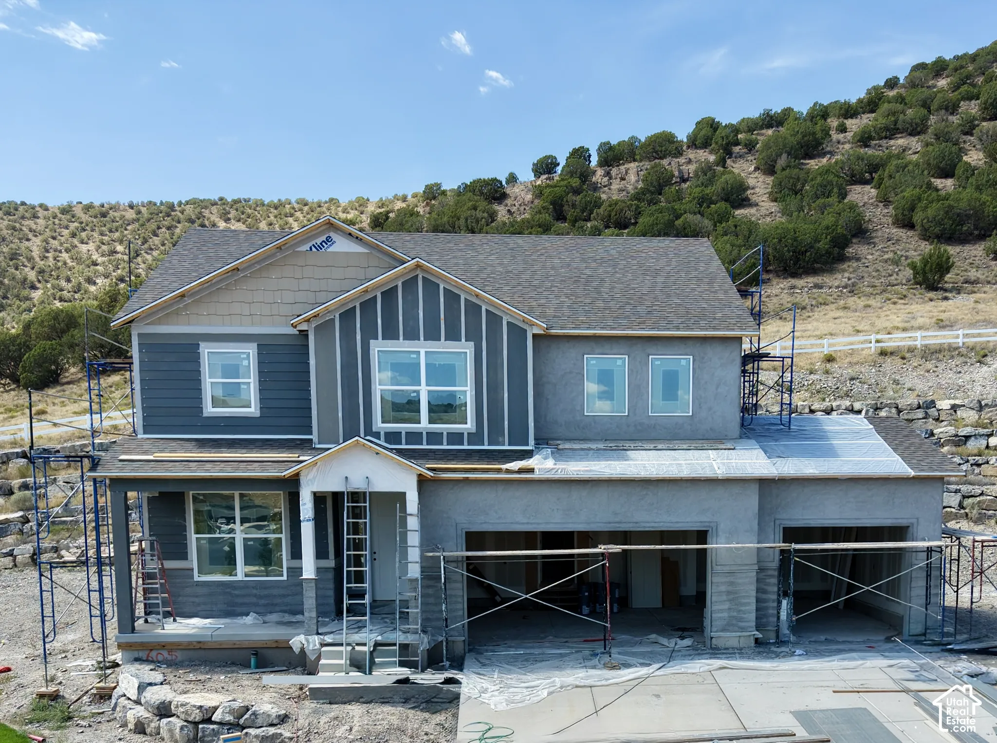 Two-story construction featuring a shingled roof, partial siding, and multiple window installations
