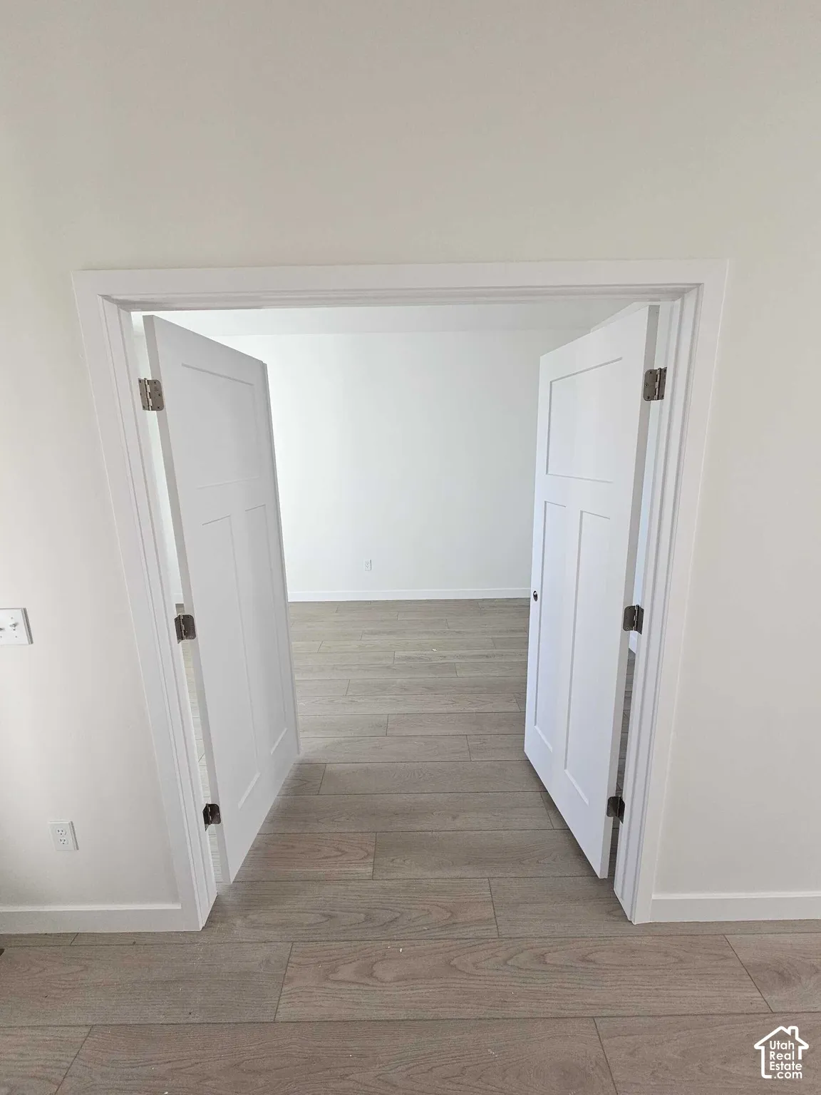 Wood-finish flooring throughout, bright white walls, and paneled interior doors