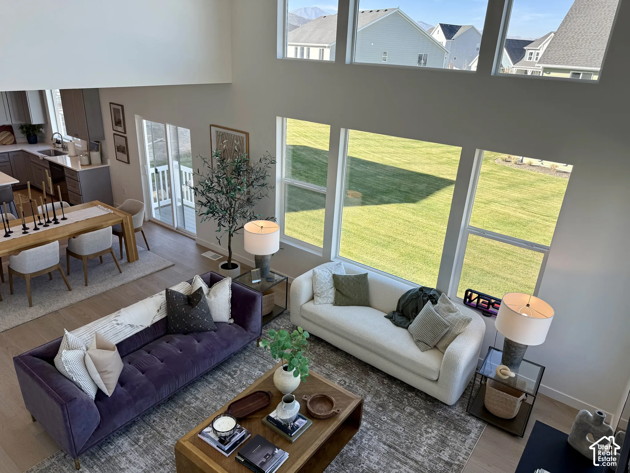 Vaulted ceilings, large windows, wood-finish flooring, sliding glass door, and a modern kitchen with grey cabinetry