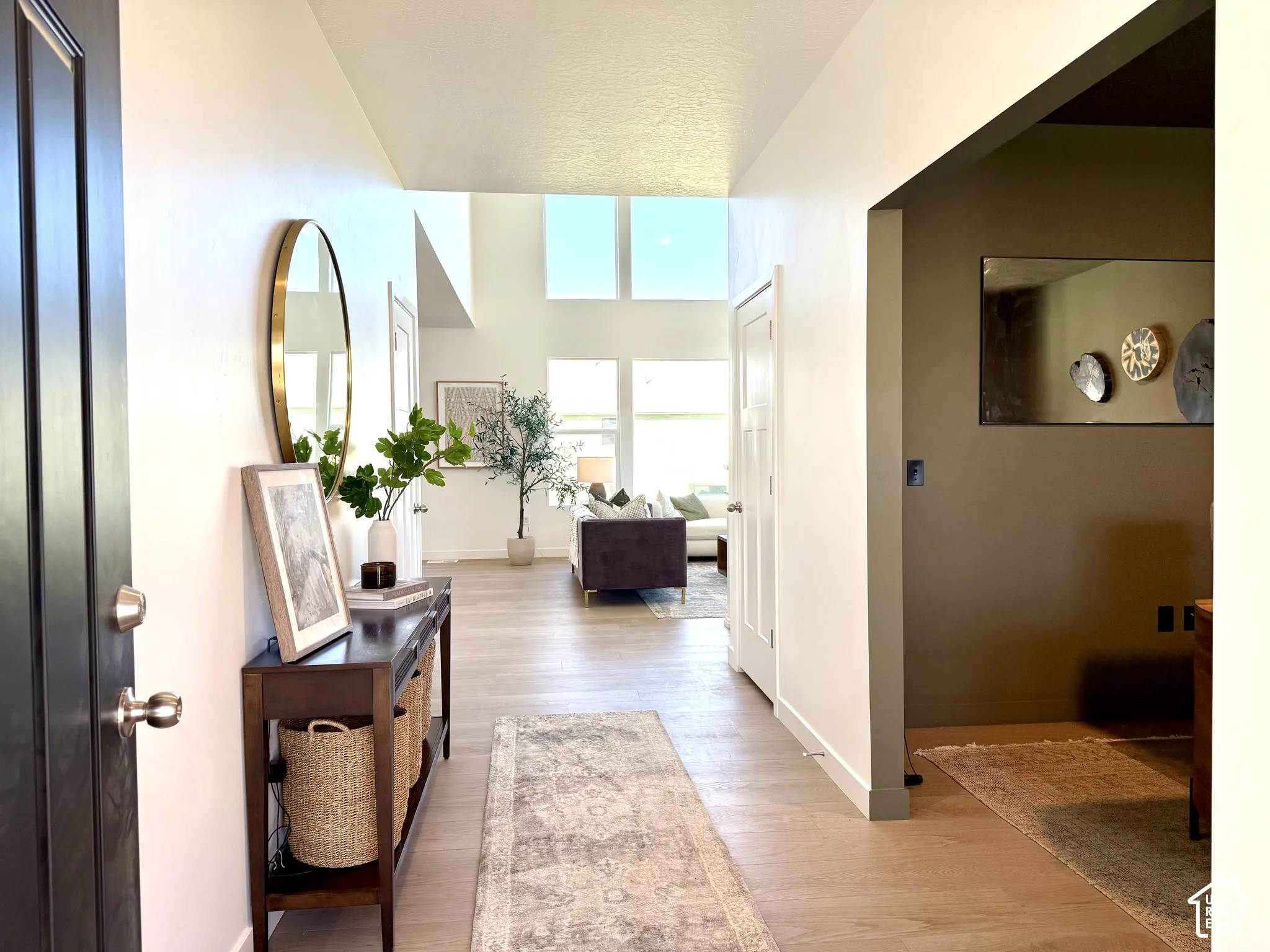 High ceilings with clerestory windows, wood-finish flooring, recessed lighting, and a dark wood console table