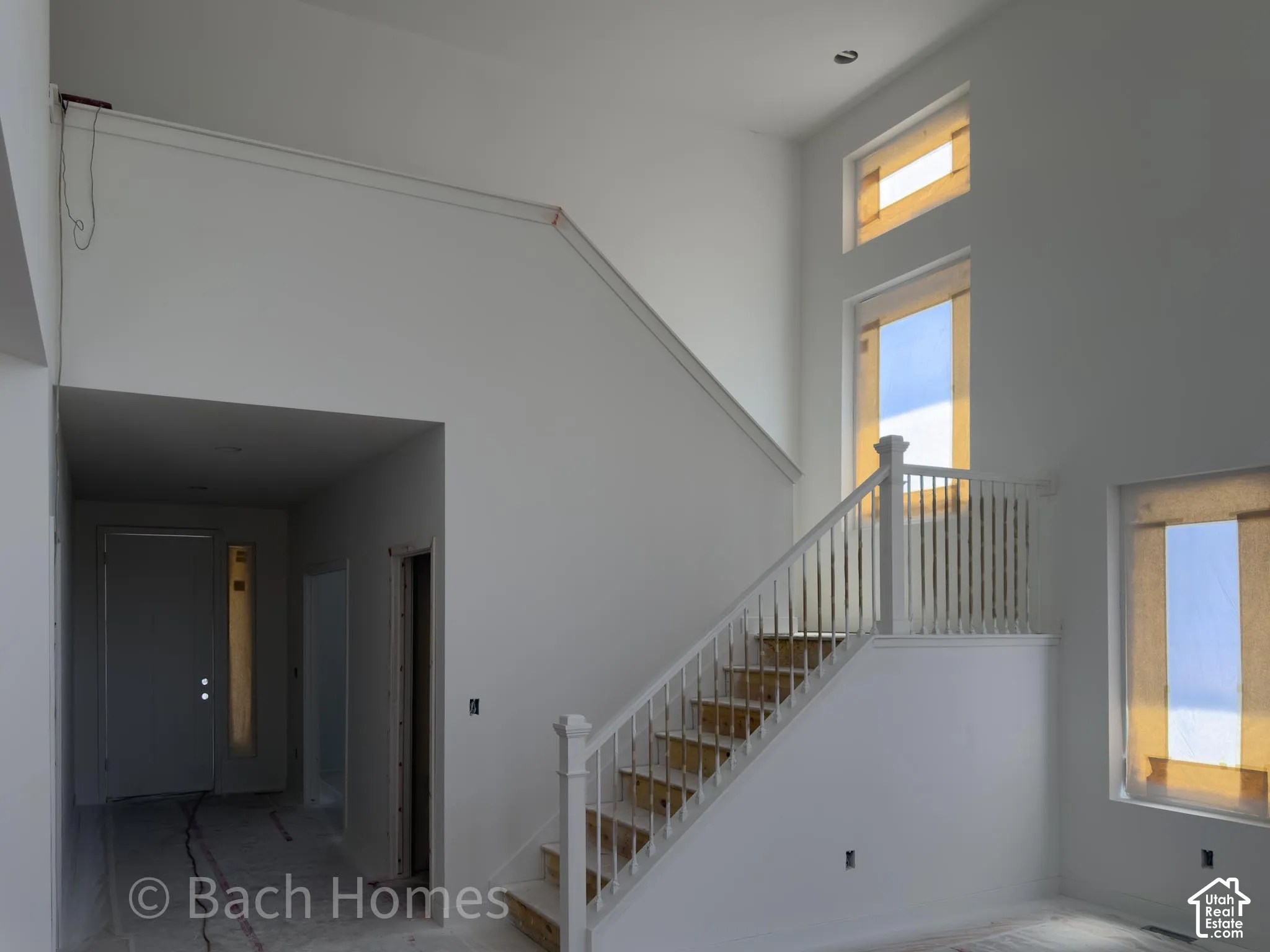 Two-story entry with a tall window array, white painted staircase, and recessed lighting