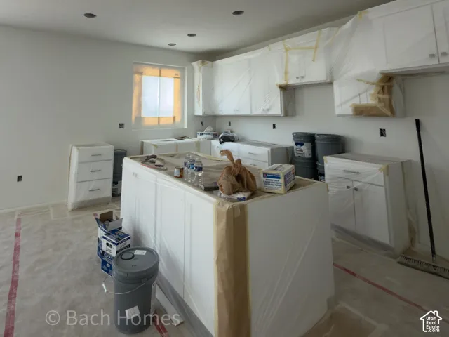 Recessed lighting, white cabinetry, a kitchen island, and a window
